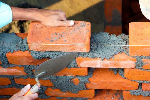 A mason laying bricks with a trowel