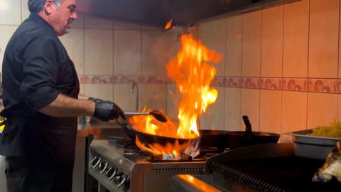 A chef flambéing in a restaurant kitchen