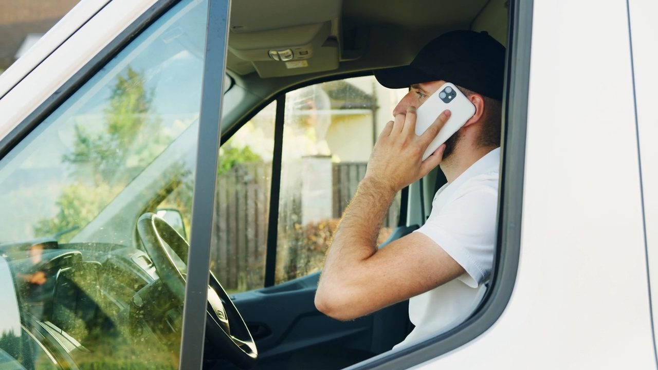 A tradesman taking a call in his work van